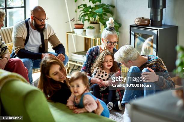 extended family gathering in living room - mom social event stock-fotos und bilder