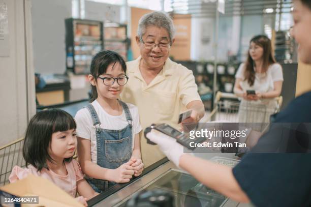 an asian chinese senior man check out and buying groceries during weekend with his granddaughter - supermarket queue stock pictures, royalty-free photos & images