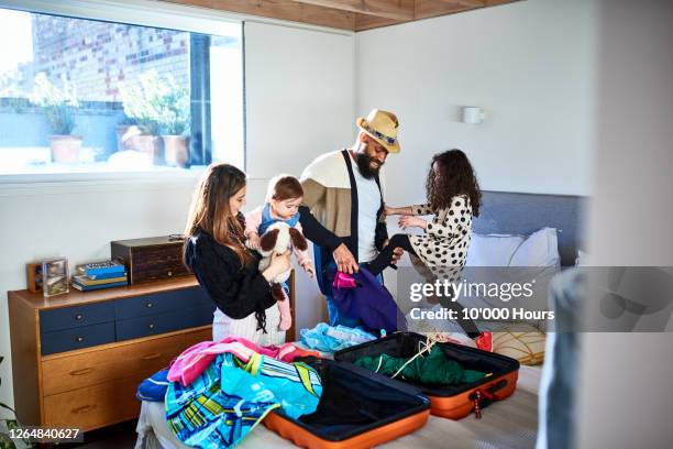 parents and two daughters packing suitcase for summer vacation - besuch zuhause sommerlich innenaufnahme stock-fotos und bilder