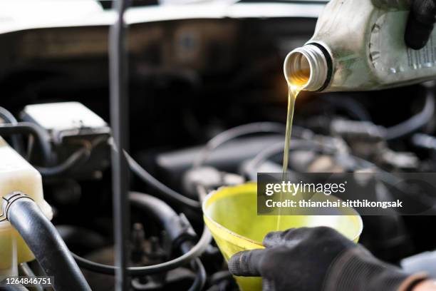 car maintenance with refueling lubricant oil - ölwechsel stock-fotos und bilder