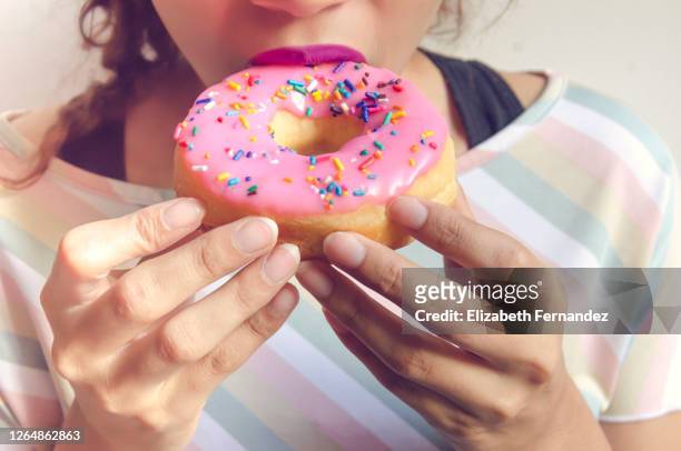 woman enjoying eating a doughnut - excess sugar stock pictures, royalty-free photos & images
