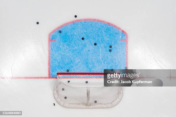 hockey net with pucks from above - ice hockey stockfoto's en -beelden