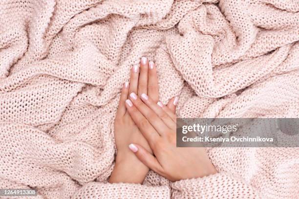 female hands manicure close up view on pink knitted sweater background. nail painting effects. manicure salon banner concept - mottled skin stockfoto's en -beelden