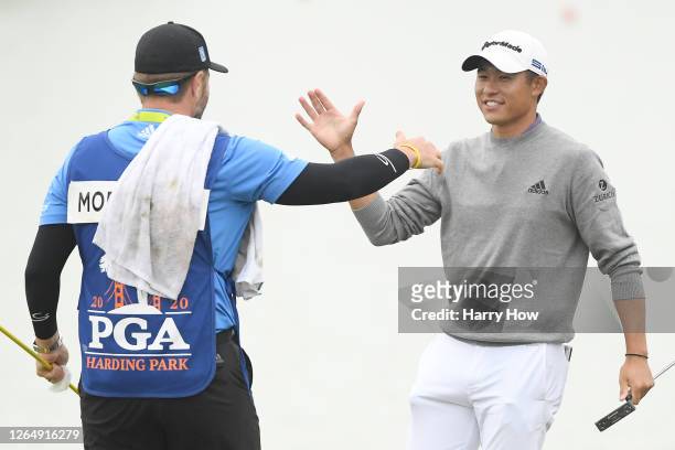 Collin Morikawa of the United States celebrates with caddie Jonathan Jakovac after making his final putt on the 18th green during the final round of...