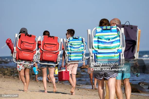 Beach-goers walk with backpack chairs as the town continues Phase 4 of re-opening following restrictions imposed to slow the spread of coronavirus on...