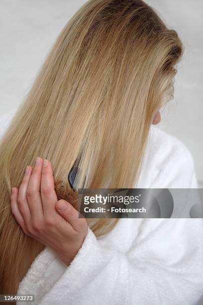woman with long blond hair using curling tongs - cheveux secs photos et images de collection