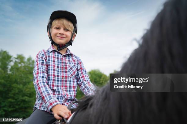 彼の黒い馬に乗って幸せな笑顔の若い男の子 - black boy ストックフォトと画像