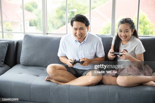 asian family father and daughter play fun video games - asian games day 9 stock-fotos und bilder