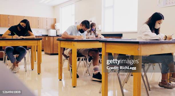 high school students in classroom wearing protective face mask - secondary school covid stock pictures, royalty-free photos & images