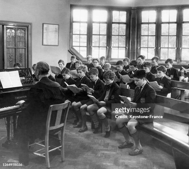 Des élèves en uniforme de l'établissement Bradford Grammar School assistent à une leçon de musique sous la direction de leur professeur au piano, le...