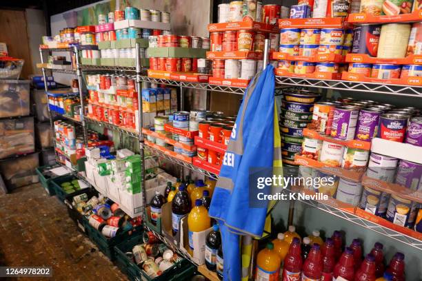 food bank shelving filled with donated tinned food ready for distribution - banco alimentar imagens e fotografias de stock