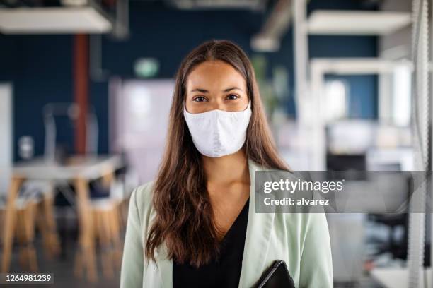 portret van een onderneemster met gezichtsmasker in bureau - beschermend masker werkkleding stockfoto's en -beelden
