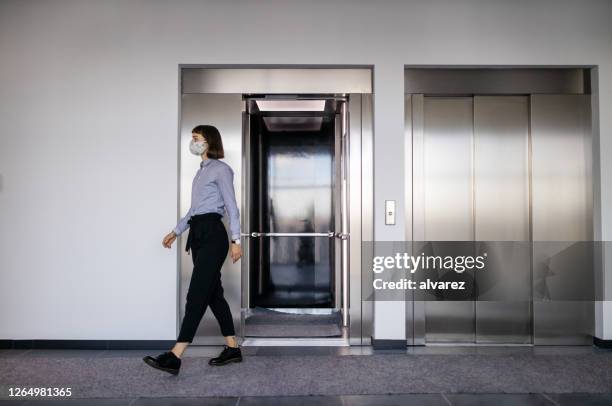 geschäftsfrau geht aus aufzug in bürolobby - lift stock-fotos und bilder