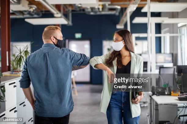 business colleagues greeting with elbow in office - protective face mask stock pictures, royalty-free photos & images