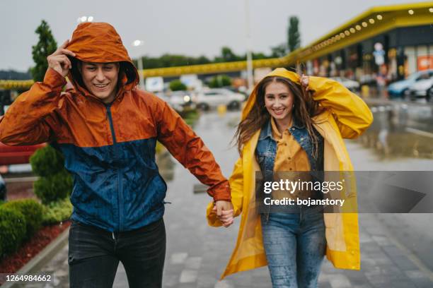 gelukkig paar dat in de stad op een regenachtige dag loopt - rain couple stockfoto's en -beelden