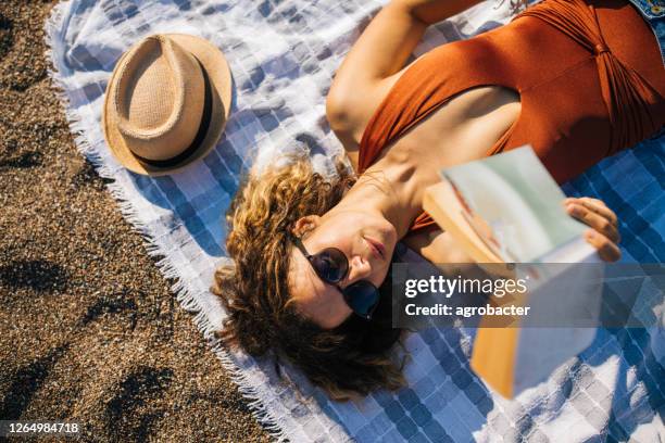 frau liegt am strand ein buch lesen - beach book reading stock-fotos und bilder