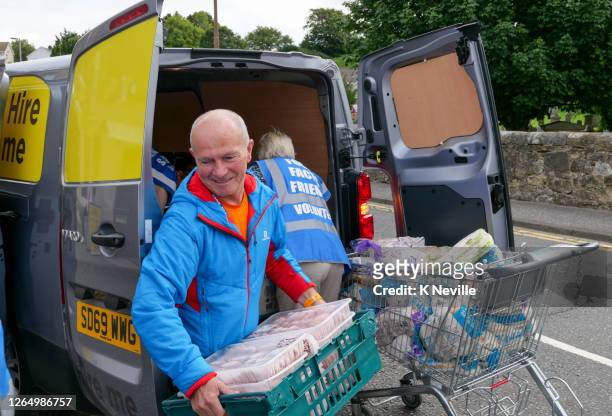 volunteers unloading a van of food at a community food bank centre - charity and relief work stock pictures, royalty-free photos & images