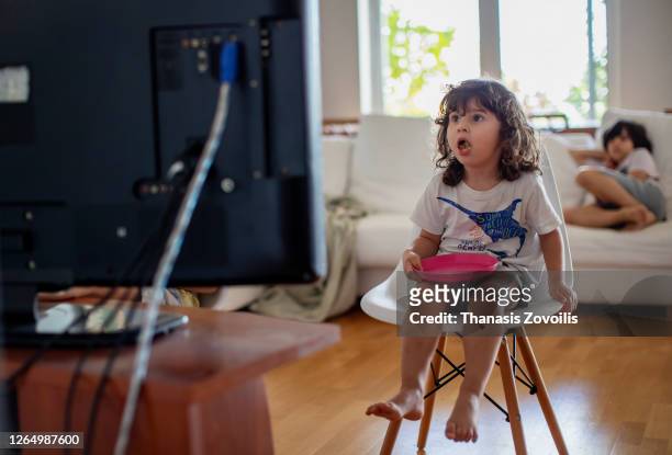 three year old boy eating in front of a television and surprised from what he see - familia viendo tv fotografías e imágenes de stock