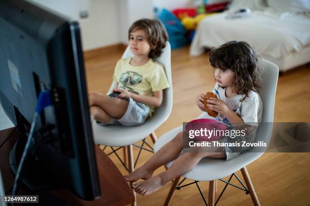 kids eating in front of a television - ungesunde ernährung stock-fotos und bilder
