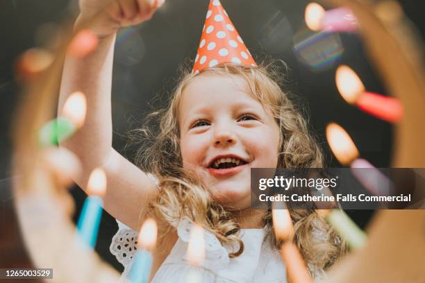 cute little girl looking down at a birthday cake, about to blow out the candles. - face down stock-fotos und bilder