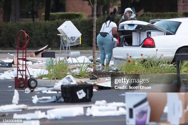 People load merchandise into a car near a looted Best Buy store after parts of the city had widespread looting and vandalism, on August 10, 2020 in...