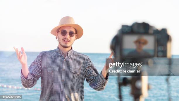 young man making video chat with his followers on social media at the sea shore. technology social media internet youth concepts. - journalist icon stock pictures, royalty-free photos & images