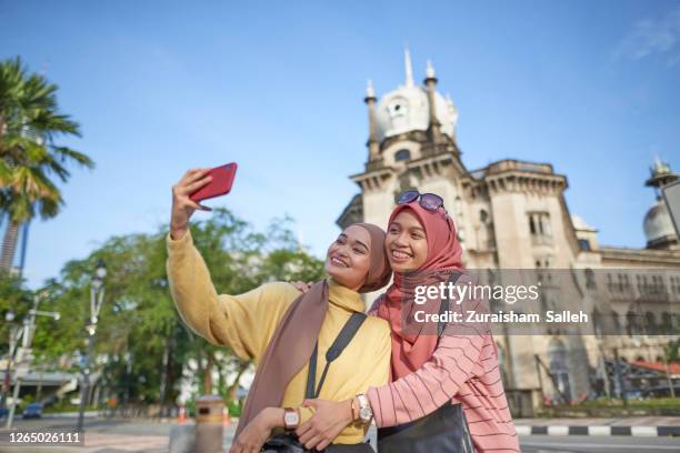 asian muslim women with hijab taking picture with smartphone standing in the middle of city street - historic building stock pictures, royalty-free photos & images