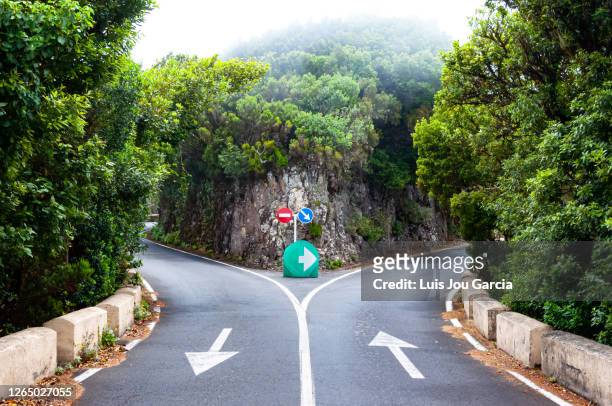 dividing road with arrow signs - road intersection stock pictures, royalty-free photos & images