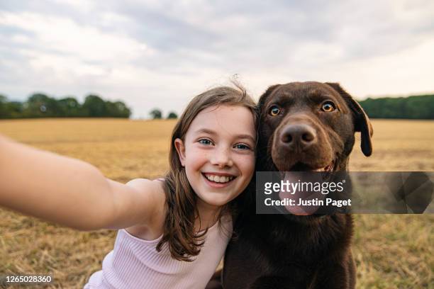 girl taking a selfie with her pet dog - hund stock-fotos und bilder