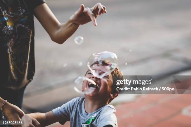 mother and son playing with bubbles, posadas, argentina - bubble wand foto e immagini stock