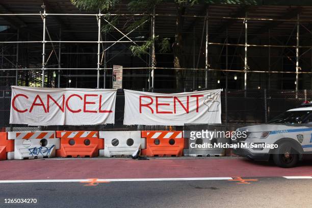 Vehicle parks in front of a "Cancel Rent" banner hung up by participants of a 'Resist Evictions' rally to protest evictions on August 10, 2020 in New...