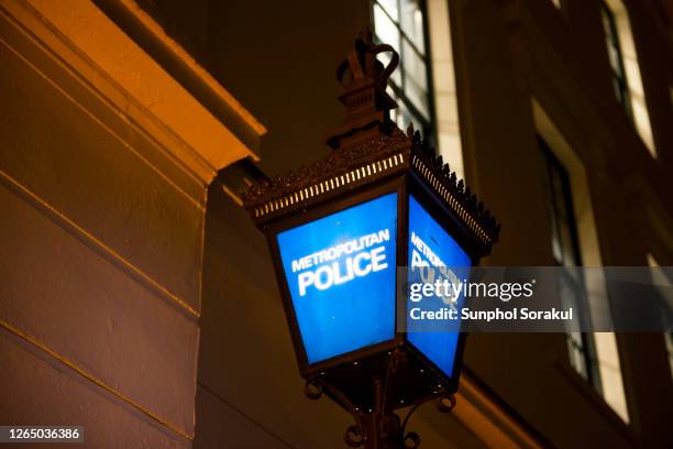 blue metropolitan police lantern in front of a police station in london at night - metropolitan police fotografías e imágenes de stock