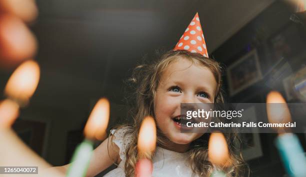 cute little girl above a birthday cake, about to blow out the candles. - birthday stockfoto's en -beelden