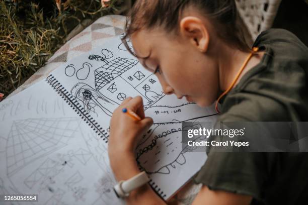 cute girl (10) drawing in a notebook in balcony at home.side view - sketch pad fotografías e imágenes de stock