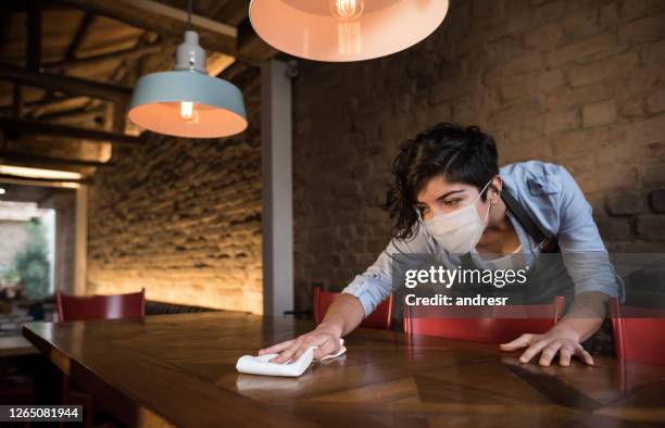 waitress at a restaurant wearing a facemask and cleaning the tables - restaurant mask stock pictures, royalty-free photos & images