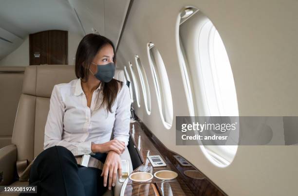 business woman traveling in a private jet wearing facemask - businesswoman mask stock pictures, royalty-free photos & images