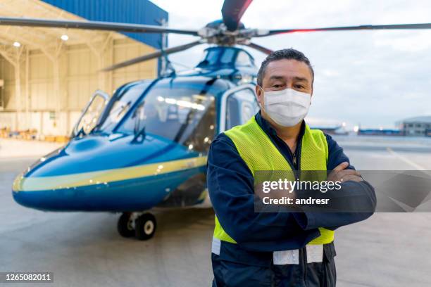 mechaniker trägt eine gesichtsmaske bei der arbeit an einem heliport - krankentransport stock-fotos und bilder