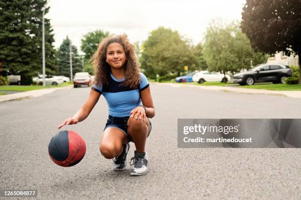 mixed-race teenage girl practicing basketball in suburb street. - canada basketball stock pictures, royalty-free photos & images