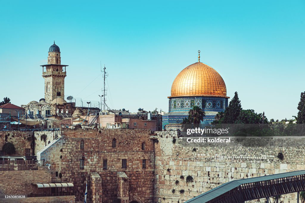 Western Wall with golden Dome of the Rock mosque against blue sky