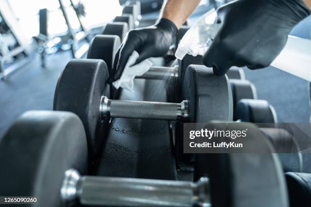 staff using wet wipe and a blue sanitizer from the bottle to clean treadmill in gym. antiseptic,disinfection ,cleanliness and healthcare, anti corona virus (covid-19) - gym covid stock pictures, royalty-free photos & images