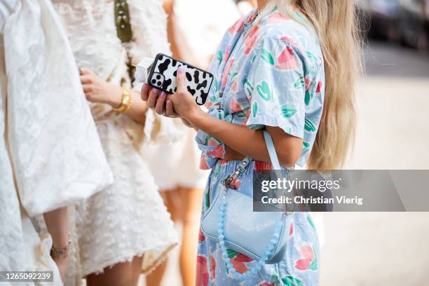 Guest with phone case with black white print, blue dress, blue bag is seen outside Malaikaraiss during Copenhagen Fashion Week SS21 on August 10,...