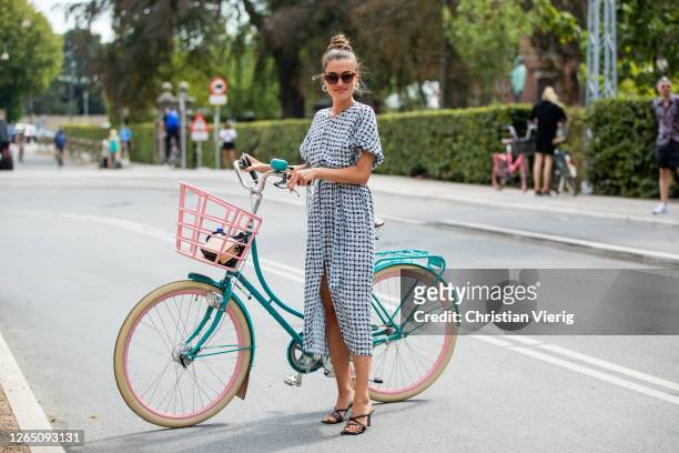 Guest is seen with her bike wearing white dress outside 7 days active during Copenhagen Fashion Week SS21 on August 10, 2020 in Copenhagen, Denmark.