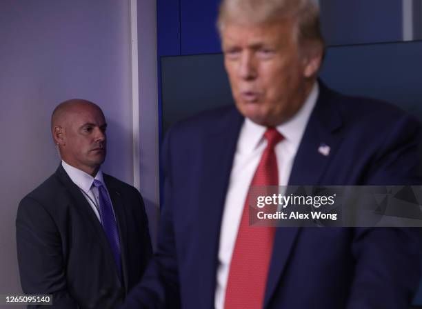 Secret Service agent stands near U.S. President Donald Trump while he speaks during a news conference at the James Brady Press Briefing Room of the...