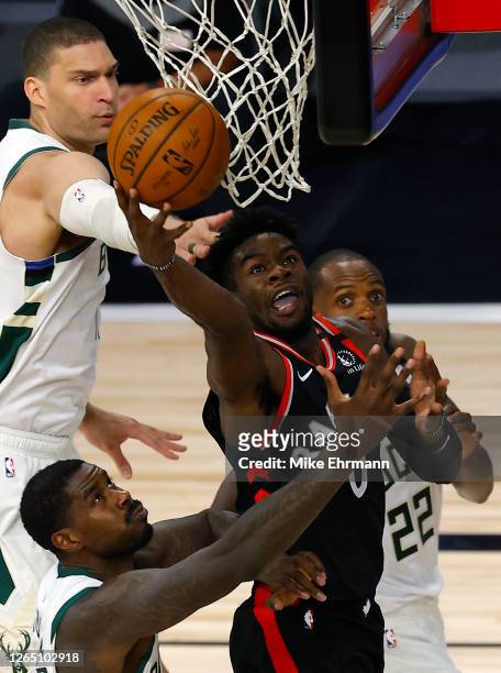 Terence Davis of the Toronto Raptors goes up for a shot against Marvin Williams, Khris Middleton and Brook Lopez of the Milwaukee Bucks during the...