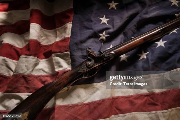 rifle lying on american flag - geweer stockfoto's en -beelden