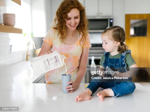 mother pouring milk for daughter (2-3) - carton milk stock pictures, royalty-free photos & images