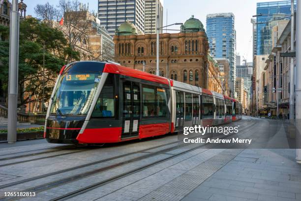 red tram, light rail on empty city street, sydney, australia - tram stock pictures, royalty-free photos & images