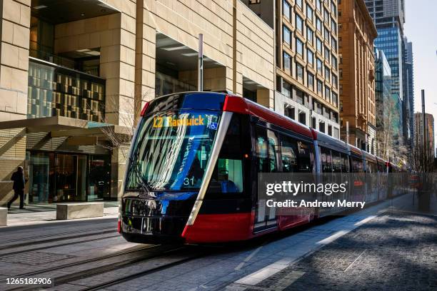 modern, new red tram, light rail on city street in luxury shopping area, sydney, australia - sydney light rail stock pictures, royalty-free photos & images