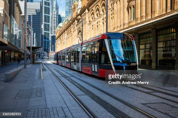 modern, new red tram, light rail on empty city street with historic sandstone building - métro léger photos et images de collection