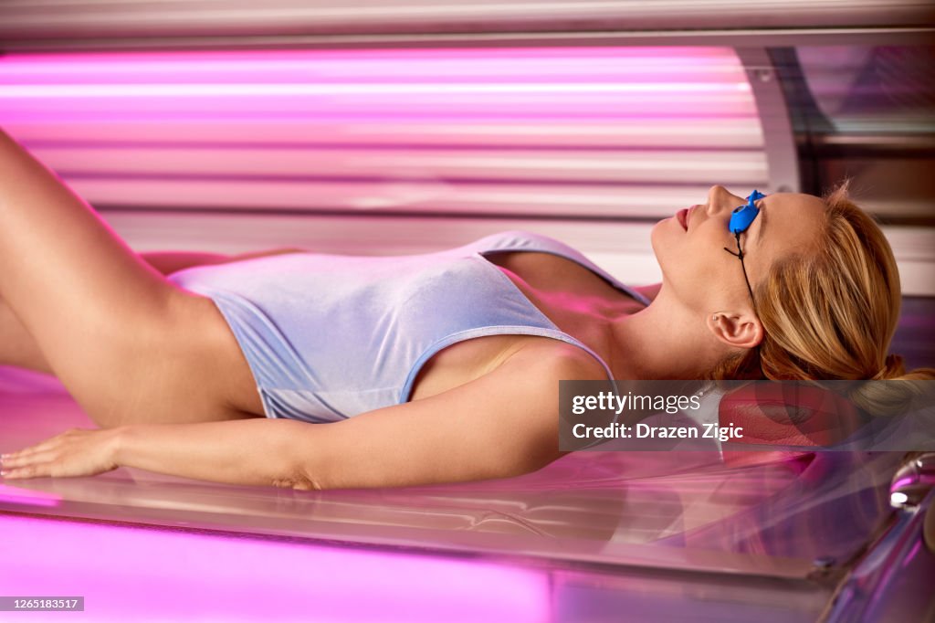 Beautiful woman tanning her skin in a solarium.